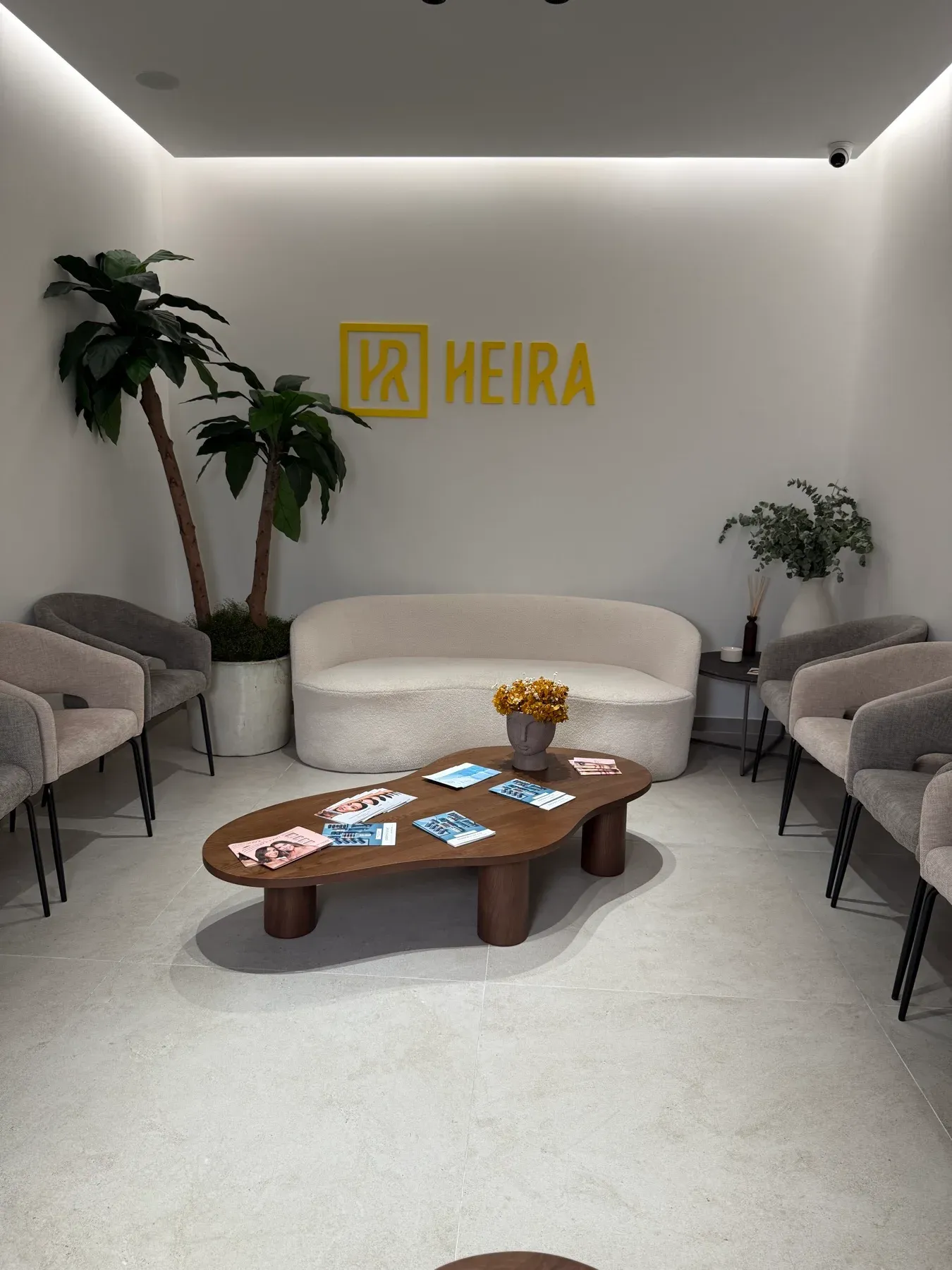 Sala de espera de HEIRA Valencia, con el logotipo amarillo y una zona de asientos.